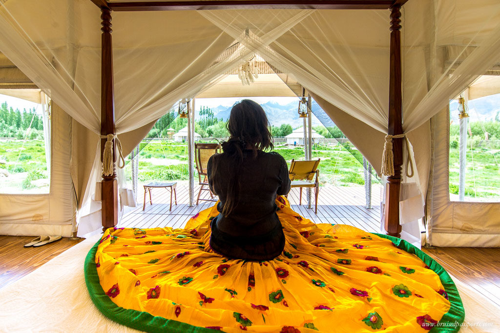 Girl sitting on bed at luxury tent at chamba camp thiksey