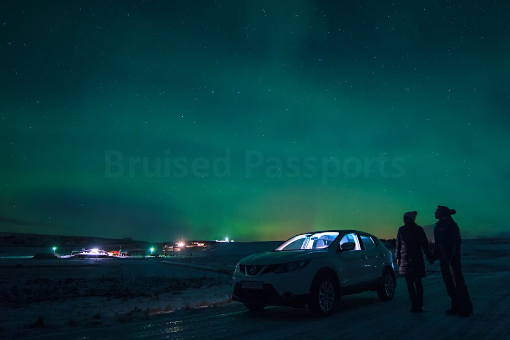 couple and their car under the Northern Lighst in Iceland