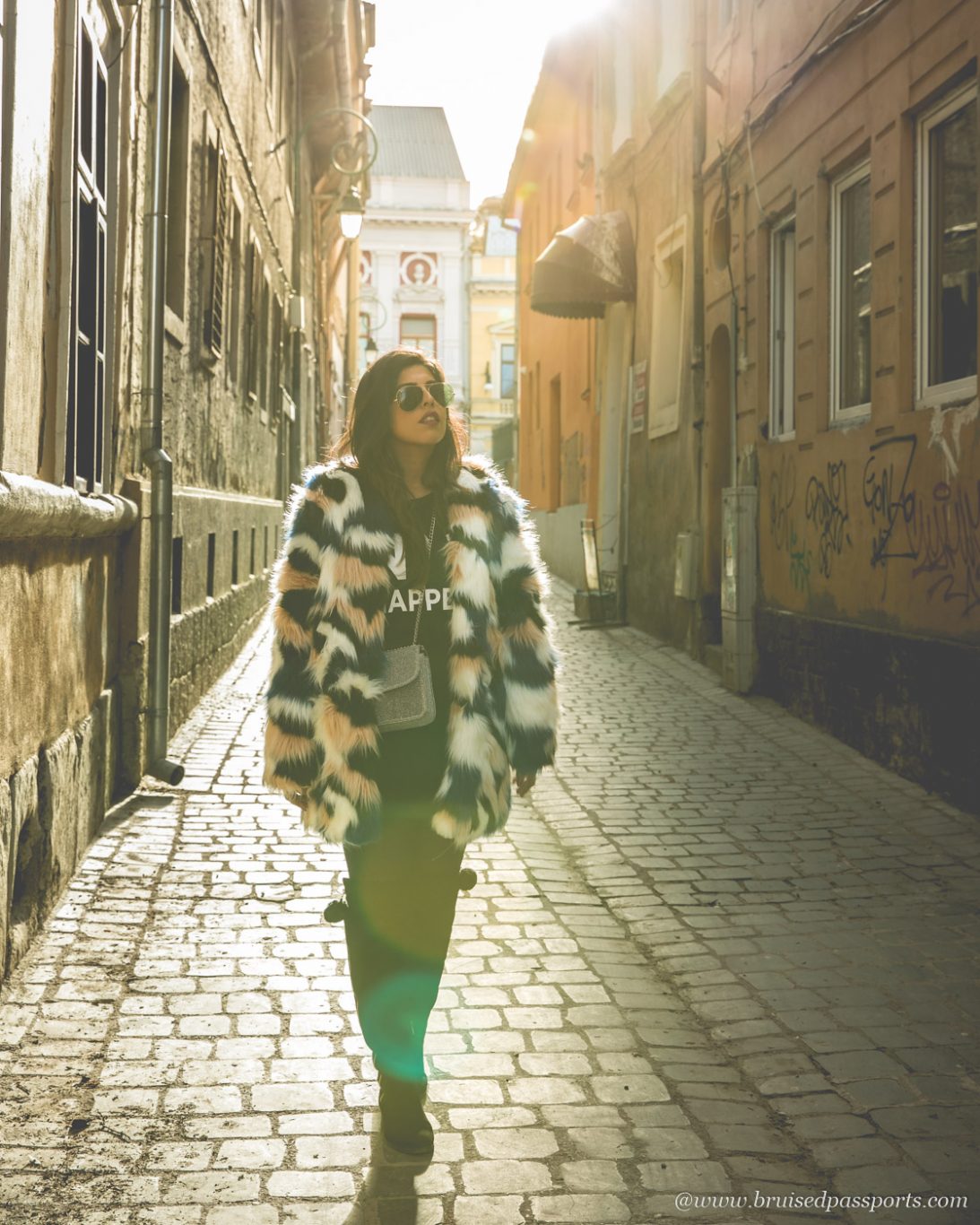 girl walking on cobbled streets in Brasov with fur jacket